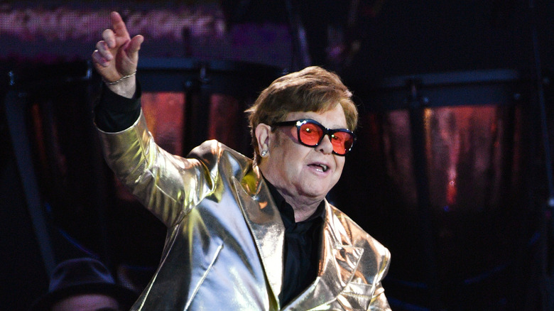 Elton John gesturing while performing onstage