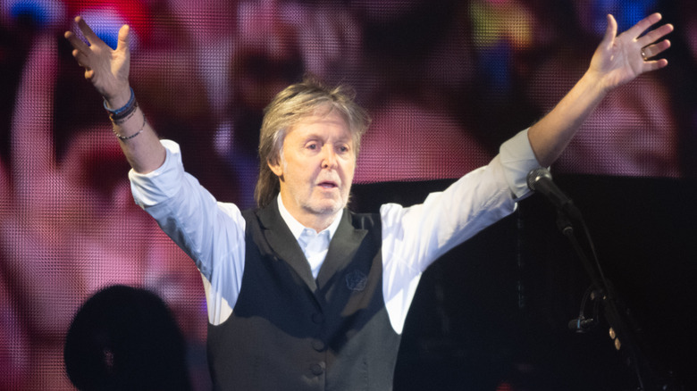 Paul McCartney raising both hands in the air onstage