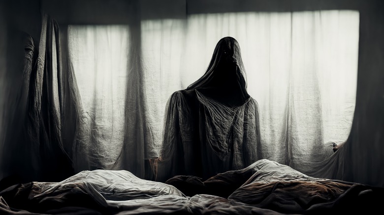 Hooded figure above a bed