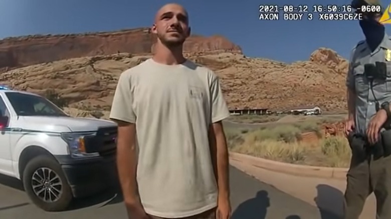 Brian Laundrie standing in front of a police car and officer in Utah