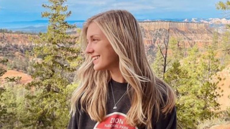 Gabby Petito smiling in front of trees and canyonlands
