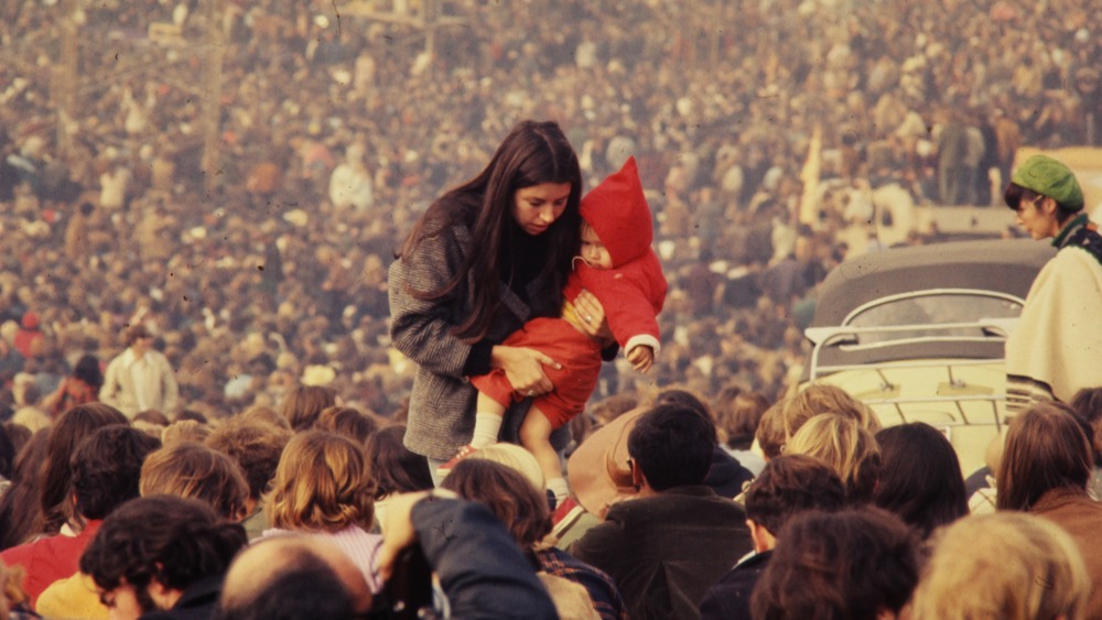 Woman carrying child through crowd of Altamont free concert in 1969