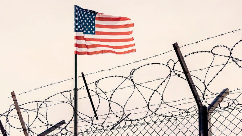 American flag by barbed wire fence