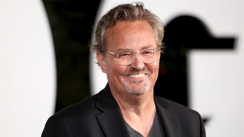 Matthew Perry glasses black suit smiling at event