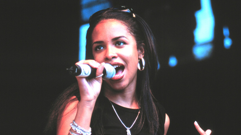 Aaliyah singing into microphone onstage