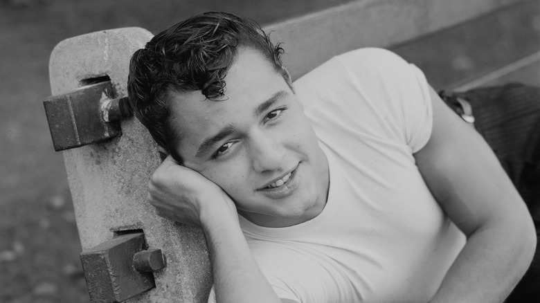 Sal Mineo lying on bench smiling