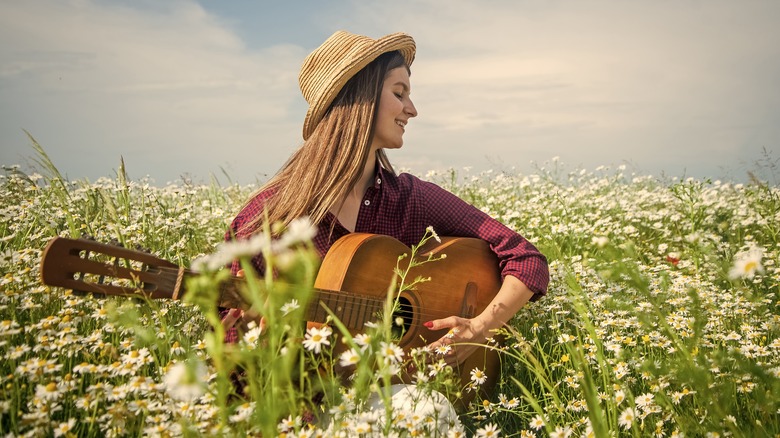 A woman playing the guitar to a field of plants