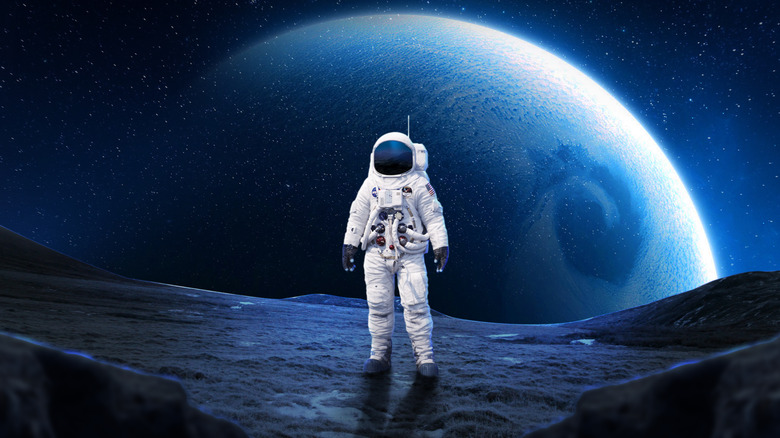 Astronaut standing on rocky surface with planet in background
