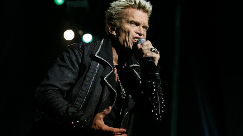 Billy Idol on stage singing holding mike black leather jacket