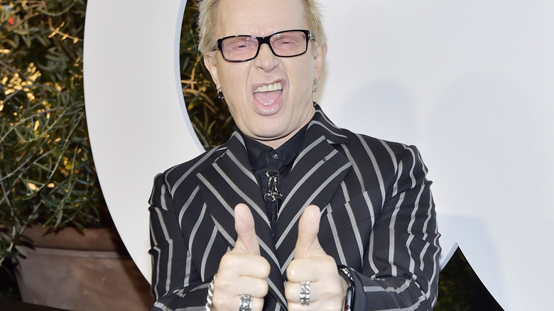 Billy Idol giving goofy thumbs up black jacket with white stripes