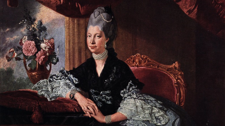 Queen Charlotte reclines by flowers