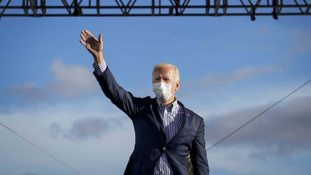 Joe Biden wearing a mask waving to supporters