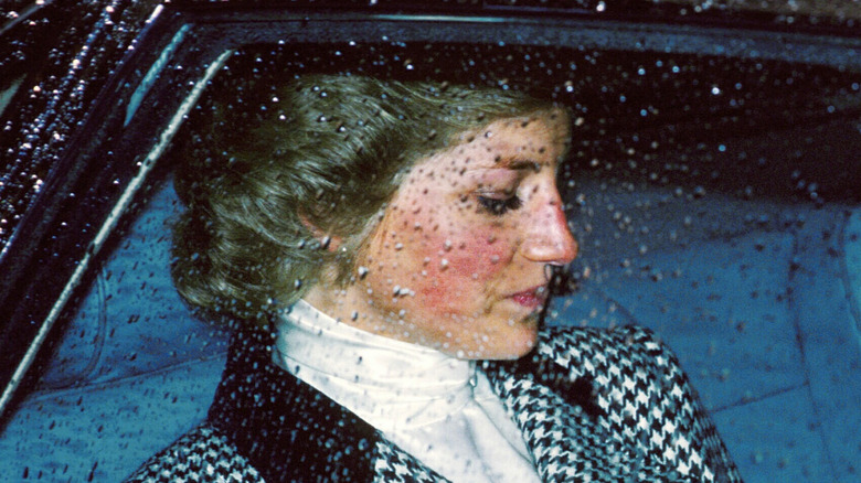 Princess Diana looking down riding in car rain