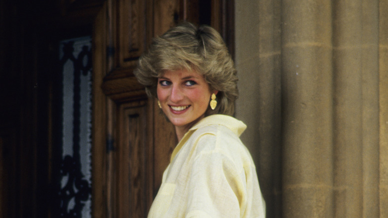 Princess Diana in yellow dress by stone wall