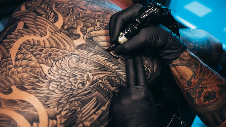 tattoo artist working on a large, intricate piece