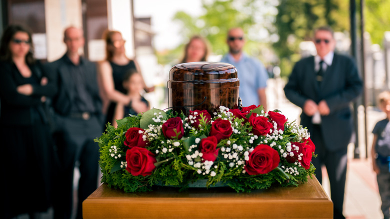 urn with flowers and mourners