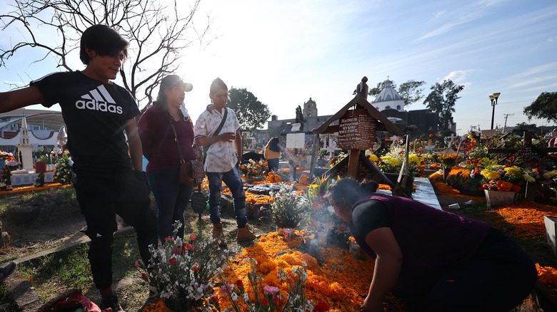 Woman lights copal incense at grave