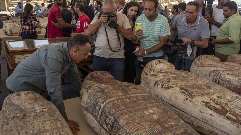 Crowd of photographers around ancient sarcophagi 