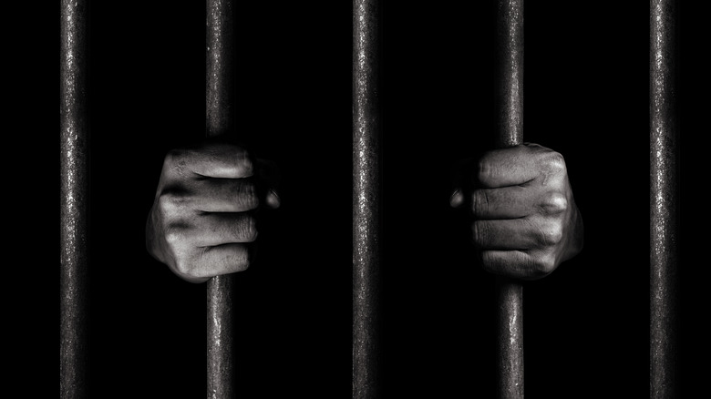 Man hands on prison bars