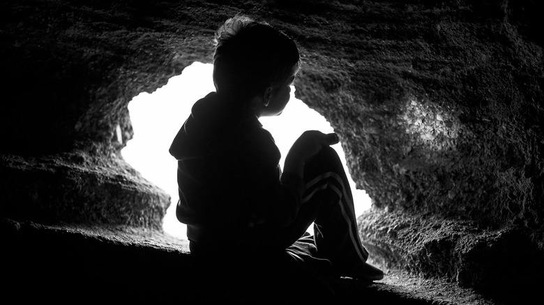 silhouette of a boy in a cave