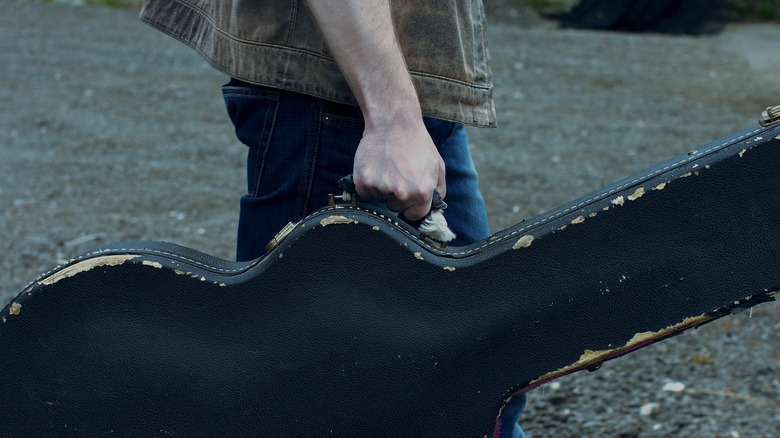 man holding guitar case