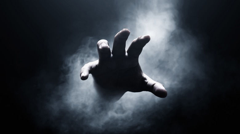 hand reaching from smoky background