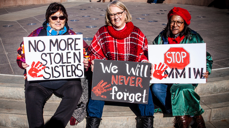 women holding MMIW protest signs