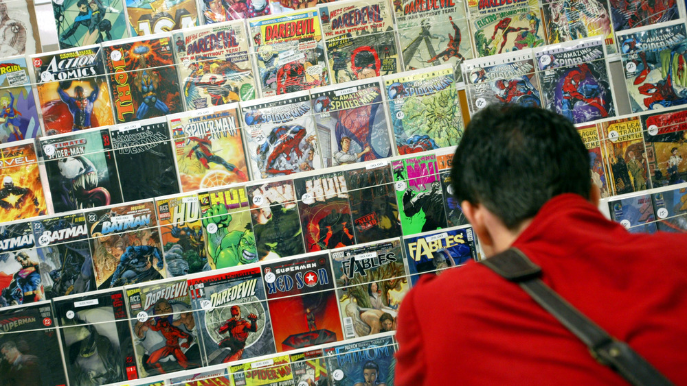 Man standing before a wall of comic books