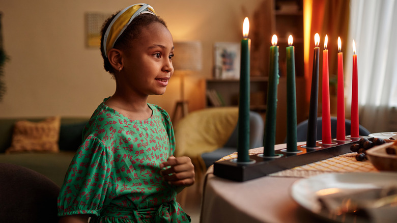 little girl looking at green Kwanzaa candles