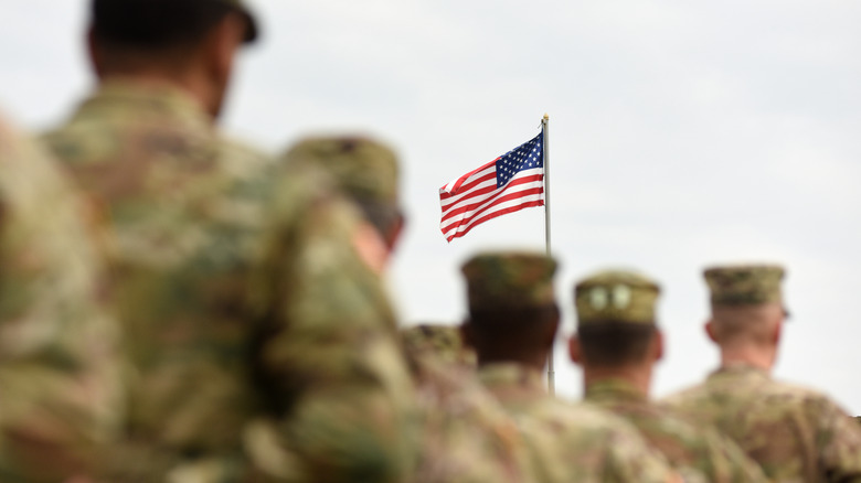 American soldiers marching near U.S. flag