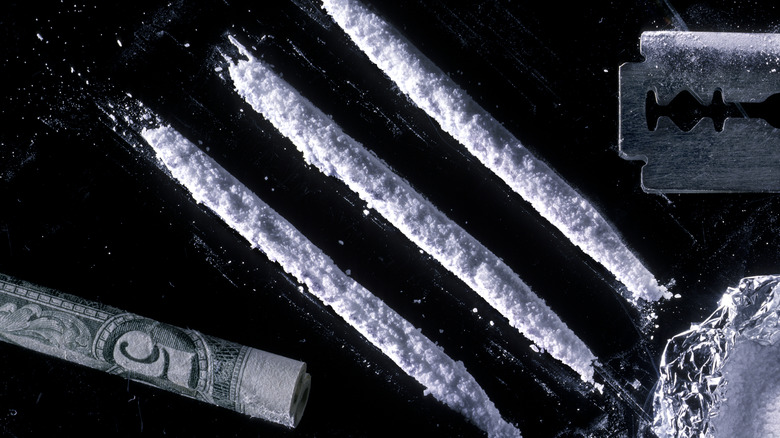 Lines of cocaine with a rolled-up bill and razor blade