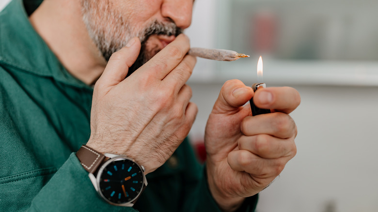 A man lighting a marijuana cigarette
