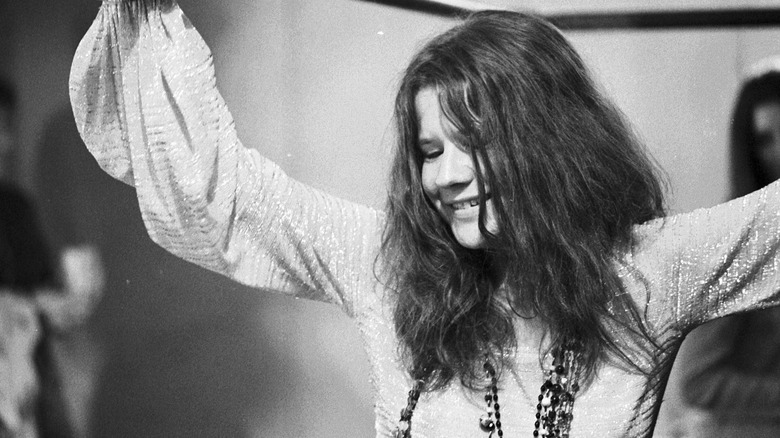Janis Joplin with arms in air, smiling