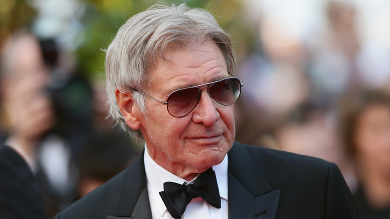 Harrison Ford in shades and a tux, smiling