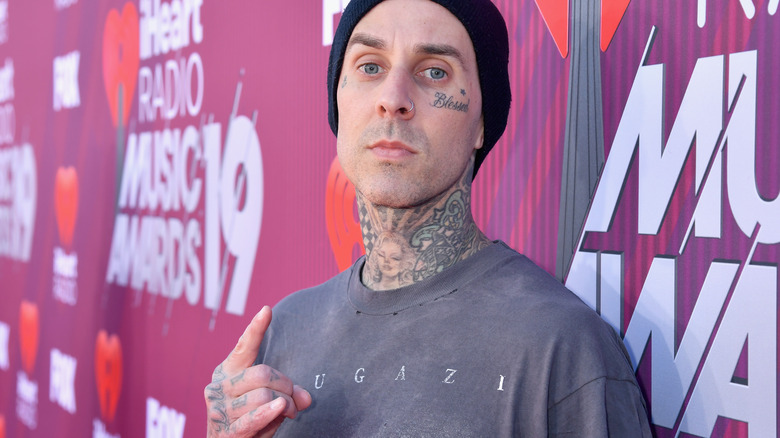 Travis Barker throws up the devil horns on the red carpet