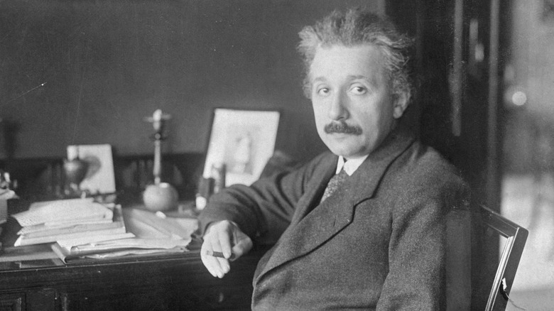 Albert Einstein seated at desk