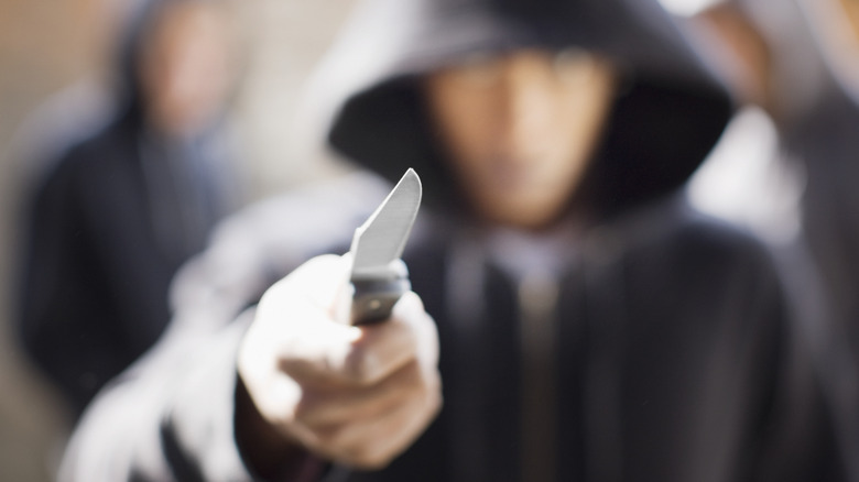 A mugger in a hoodie with a knife