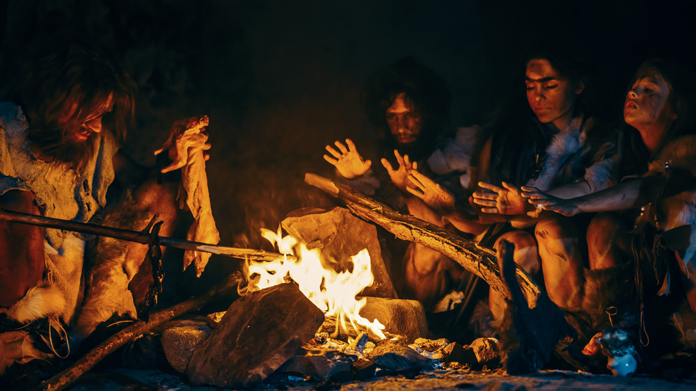 Prehistoric humans gathered around a fire