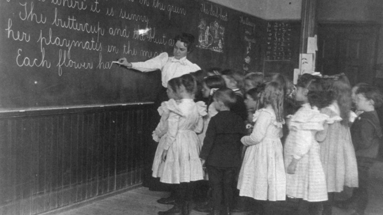 Students watch teacher write on blackboard