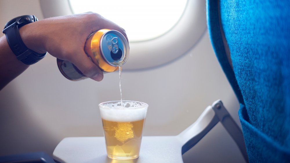 A man pouring beer into a cup on a plane