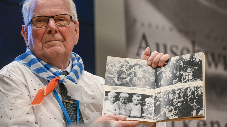 Auschwitz survivor holding photos of camp children