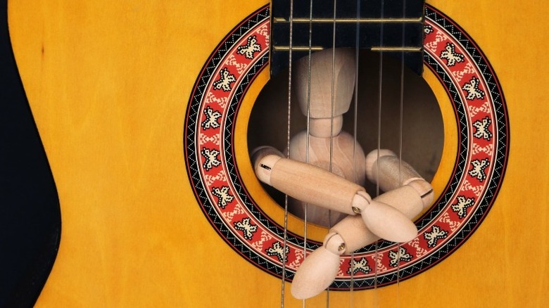 Figure imprisoned behind guitar strings