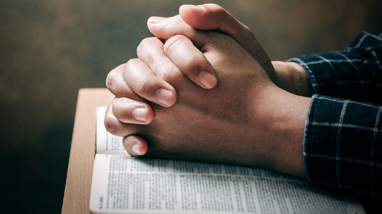 hands praying on Bible 