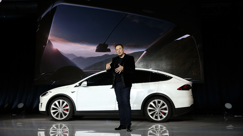 Elon Musk speaking in front of Tesla car