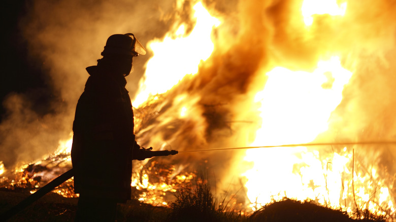 Firefighter hosing down giant fire