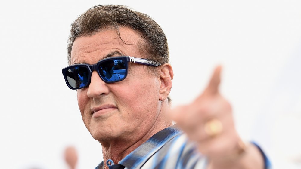 Sylvester Stallone wears some sunglasses and points at the camera