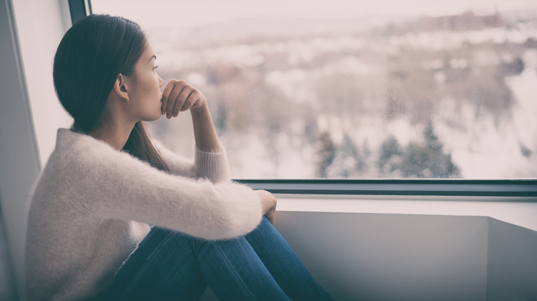 Lady staring out of window at winter