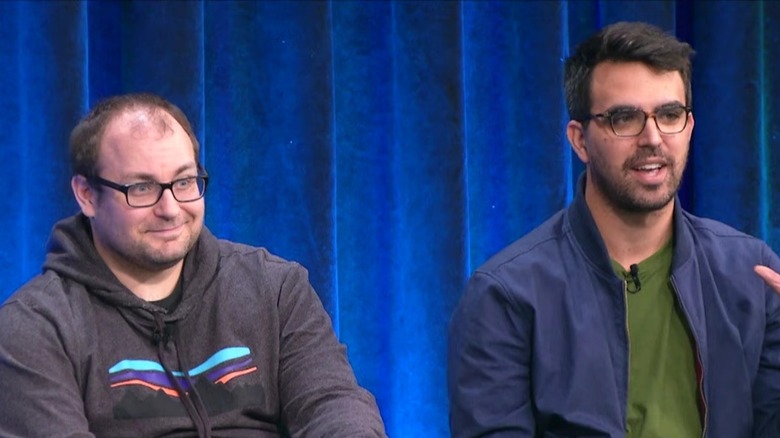 Alex Goldman and PJ Vogt glasses seated blue curtain