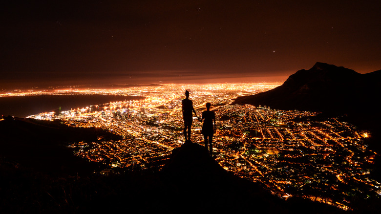 Silhouetted people holding hands, overlooking Cape Town, South Africa.