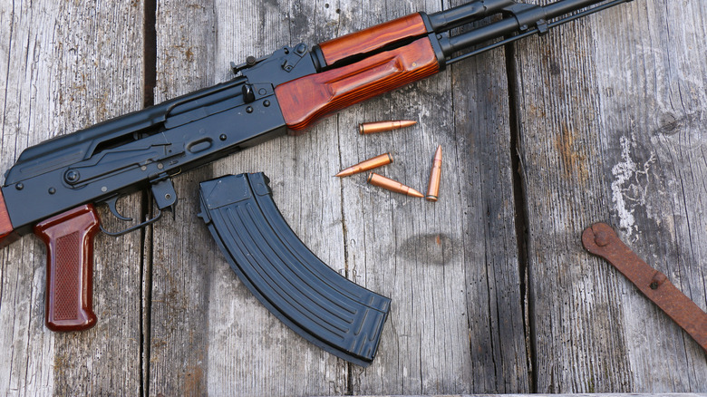 AK-47 on a wooden porch floor with four bullets next to it